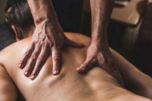 Hands massaging the back and the thoracic spine